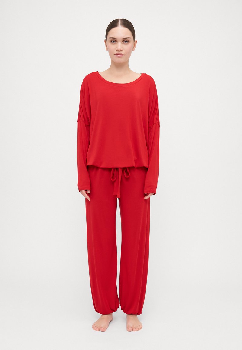 Red loungewear set featuring a loose long-sleeve top and elastic-waist pants with a drawstring, made of soft, smooth fabric.
