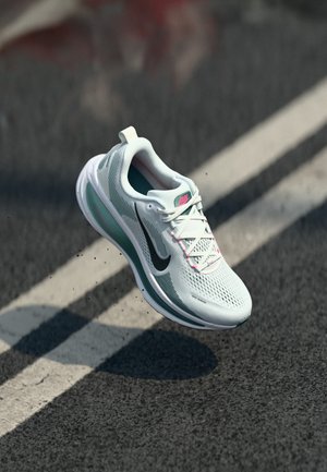 Chaussure de course bleu clair avec une tige en mesh et un swoosh noir. Présente des accents roses, une semelle texturée et un design distinct de semelle intermédiaire amortie.