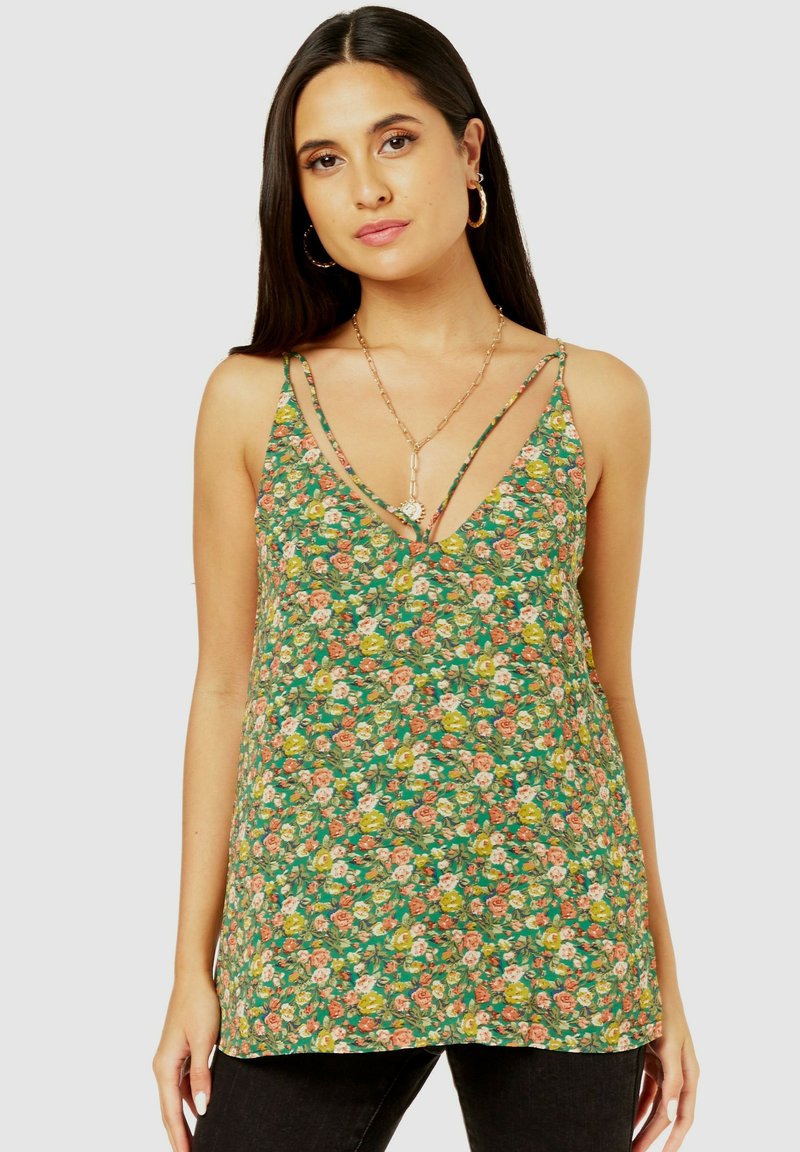 Floral green tank top featuring a deep V-neck, thin straps, and a loose fit; bright flowers in shades of pink, yellow, and white throughout.