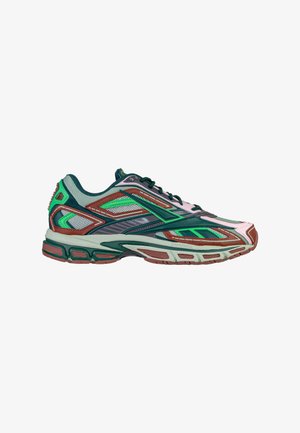 Zapatilla de running con malla y superposiciones sintéticas en verde, marrón y gris, suela gruesa y acolchada y cordones negros, mostrada desde el lado exterior.