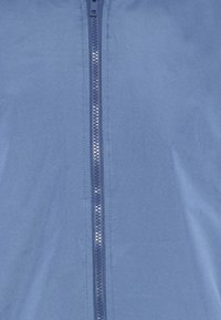 Giacca zip-up blu con una texture in tessuto liscia, vestibilità slim e una cerniera frontale con finitura metallica.