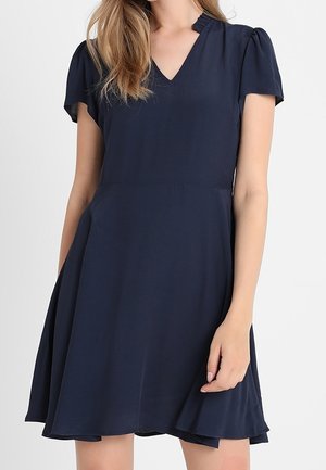 Marineblauwe jurk met korte mouwen, een V-hals, een uitlopende rok en een gestructureerde stof. Heeft subtiele pofmouwen en een vloeiende ontwerp.