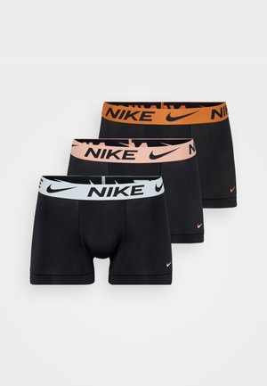 Bóxers negros con una cinturilla de logo de Nike en color melocotón. El material parece suave y ajustado, resaltando un diseño a medida.