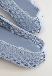 Bottines tissées bleu clair à enfiler avec une semelle lisse, présentant des détails tressés et un design à bout rond. Fabriquées en matériau synthétique.