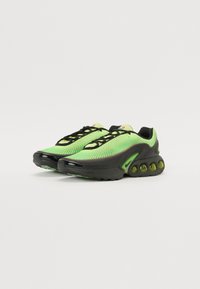 Green mesh sneakers with black accents, featuring rounded heel bubbles, flat laces, and a curved design for breathability and support.