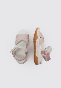 Sandalias de color rosa claro y beige con una suela de goma texturizada. Las correas cruzadas cuentan con bandas de tela suave y cierres ajustables en el talón.