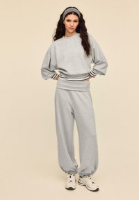 Gray sweatshirt and matching joggers made of soft fabric. Sweatshirt has wide sleeves and striped ribbed cuffs. Features elasticized waistband.