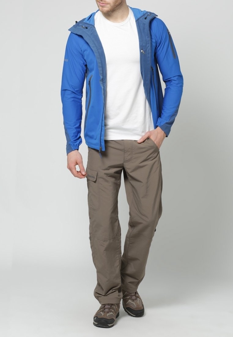 Veste légère bleue pour homme avec des accents gris, associée à un pantalon cargo beige. Les deux pièces présentent des éléments de design fonctionnels pour une utilisation en extérieur.