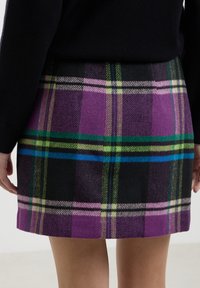 Gonna in plaid di lana con vivaci motivi a scacchi viola, nera e verde. Il tessuto ha una consistenza morbida e un taglio dritto, che arriva a metà coscia.