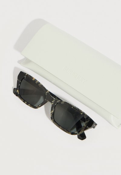 Μαύρα γυαλιά ηλίου με μπεζ και μαύρο πλαίσιο με σχέδιο, δίπλα σε λευκή θήκη γυαλιών με την επωνυμία Burberry, σε λευκό φόντο.