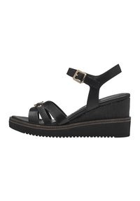 Black wedge sandals with crossover straps, adjustable ankle strap, textured heel, and a rubber sole. Feature gold-toned buckle detail.