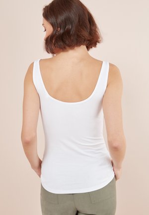 Witte tanktop met een ronde rug, gemaakt van een gladde stof. De pasvorm is strak, met brede schouderbanden en een gebogen zoom.