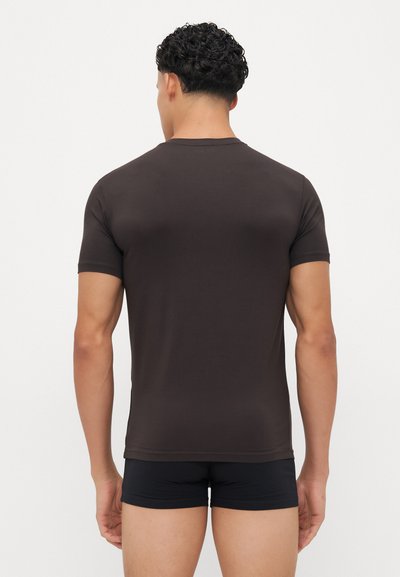 T-shirt castanho de mangas curtas feito de tecido suave, design ajustado, com um decote redondo e costas limpas, combinado com calções pretos.