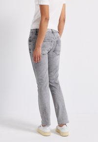 Grijze denim jeans met een rechte pasvorm, licht vervaagde textuur, vijf zakken en een medium hoge taille. Gekleed met witte schoenen.
