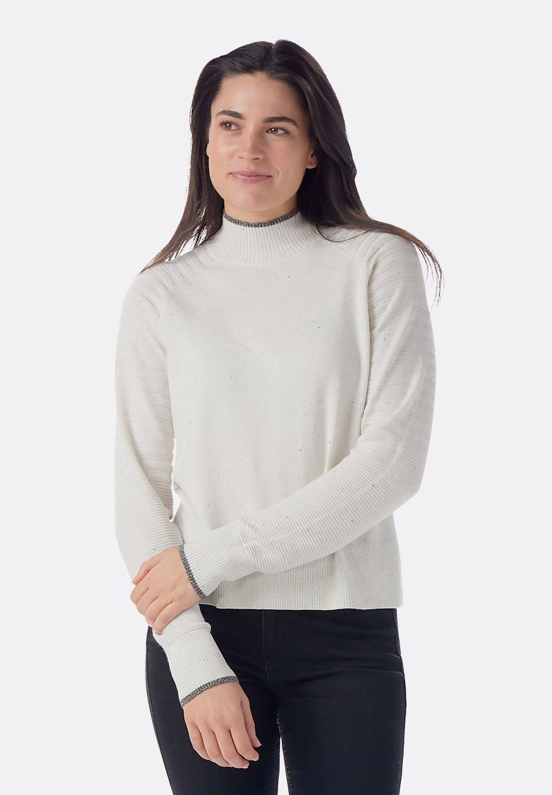 Maglione bianco con collo alto e texture a coste. Presenta polsini scuri a contrasto e una vestibilità morbida. Piccole macchie sottili sulla stoffa.