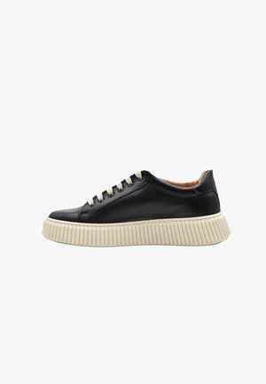 Sneaker nera bassa con suola spessa crema a coste e lacci crema, mostrata di profilo su sfondo bianco.