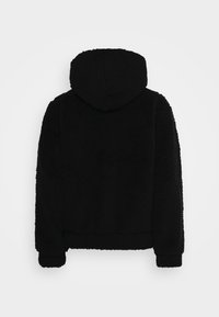 Chaqueta de forro polar negra con capucha, que presenta una superficie suave y texturizada, así como puños acanalados, diseñada para uso casual y cálido.