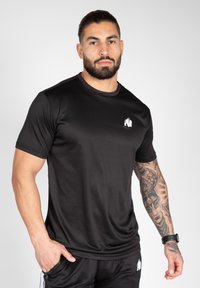 Black athletic t-shirt made from moisture-wicking fabric, featuring short sleeves and a small white logo on the chest.