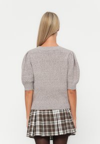 Gray knitted sweater with short puff sleeves, paired with a plaid skirt featuring brown and white tones. Soft texture, casual design.