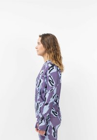 Langärmliges Oberteil aus gemustertem Stoff mit lila, blauem und schwarzem Tarnmuster. Weiche Textur, taillierte Passform mit Daumenlöchern an den Ärmeln.