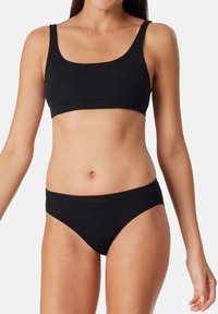 Top corto a righe nere e bikini abbinato, con un design semplice caratterizzato da spalline larghe e una texture liscia.