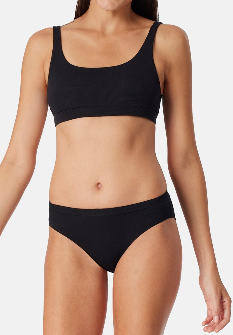 Top corto a righe nere e bikini abbinato, con un design semplice caratterizzato da spalline larghe e una texture liscia.