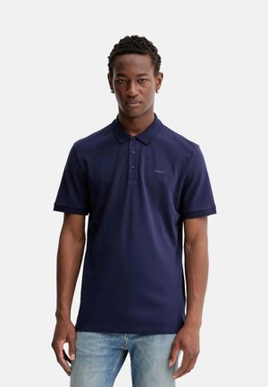 Polo en color azul marino, hecho de algodón, con cuello, tapeta de tres botones y pequeño logo bordado en el lado izquierdo del pecho.