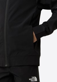 Jachetă neagră pentru bărbați cu fermoar, având o textură netedă, design ajustat, închidere cu fermoar și buzunare laterale. Logo de marcă pe tiv.