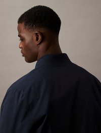Marineblauw collshirt met een gladde textuur, met een strak ontwerp en geen zichtbare patronen, gezien van de zijkant en achterkant.
