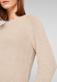 Pull beige en maille avec un motif texturé, doté d'un col bateau et de manches longues. Confectionné dans un matériau doux et respirant.