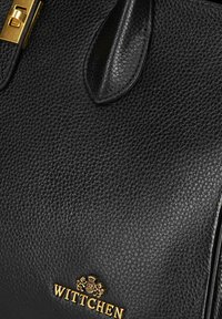 Borsa a mano in pelle nera con superficie testurizzata, hardware dorato e un logo prominente con la scritta "WITTCHEN" impresso sul fronte.