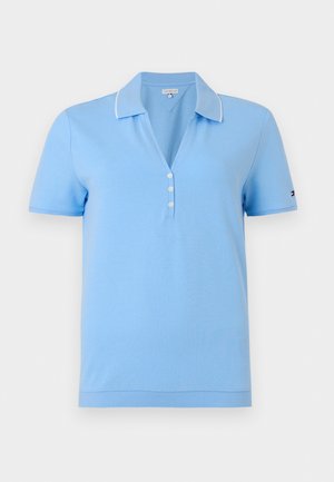 Polo bleu clair à manches courtes avec bordure blanche sur le col et trois boutons blancs à l'encolure.