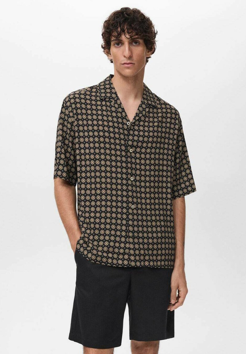 Zwarte T-shirt met korte mouwen, voorzien van cirkelvormige gouden en bordeauxrode patronen, met een losse pasvorm en knoopsluiting, gecombineerd met donkere shorts.