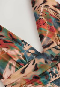 Tessuto di raso multicolore con motivi astratti in rosa, rosso, blu e nero. Texture morbida con una leggera lucentezza. Dettaglio di design avvolgente.