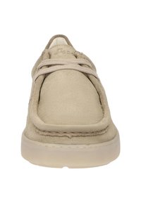 Baskets en suede beige avec un embout arrondi, un design minimaliste et une tige texturée. Elles possèdent des lacets assortis et une semelle en caoutchouc de couleur claire.