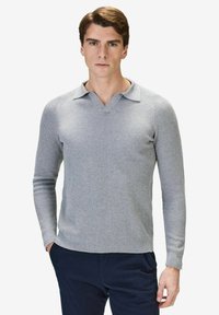 Grå ribbad tröja med långa ärmar, V-ringning och en strukturerad tyg. Plagget har en figurnära design och en enhetlig färg.