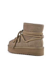 Botas de tobillo de ante marrón con punta redonda, suela de goma gruesa y cordones planos envueltos alrededor de la parte superior para mayor detalle y soporte.