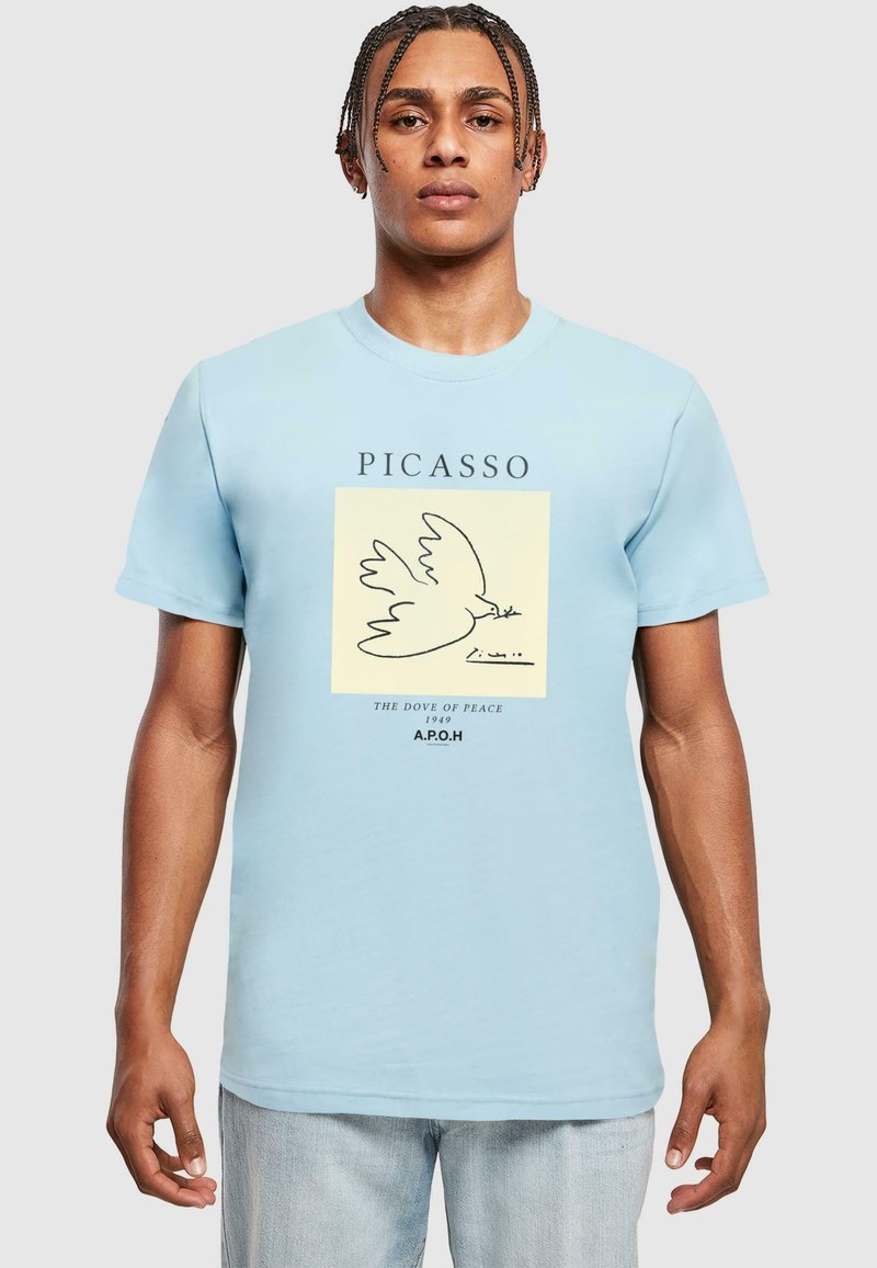 Šviesiai mėlyna marškinėliai su juoda baltojo balandžio piešiniu ant kreminės kvadratėlio, su užrašu "PICASSO" ir "TAIKOS BALANDIS 1949" apačioje.