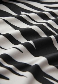 Szövet hullámos fekete-fehér csíkos mintával, sima textúrával, változó szélességű csíkokkal, amelyek vizuális kontrasztot teremtenek.