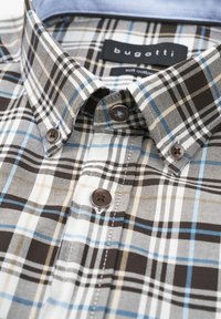 Karierte Bluse aus weichem Baumwollstoff in Braun, Blau, Beige und Weiß, mit Kentkragen und braunen Knöpfen. Markenschild sichtbar.