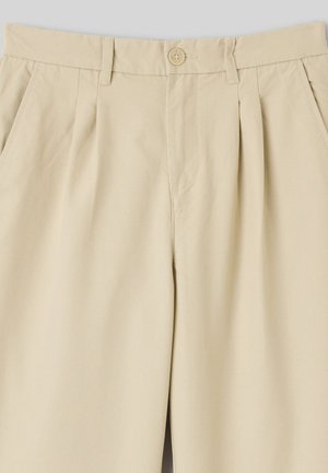 Pantalon beige plissé avec fermeture boutonnée, passants pour ceinture et poches avant inclinées, confectionné dans un tissu léger et lisse.