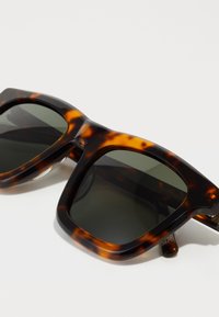 Tortoiseshell sunglasses with a square shape, dark lenses, and thick, glossy plastic frames featuring orange and brown patterns.