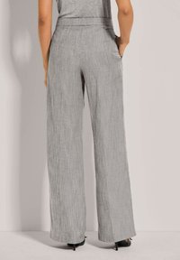 Wijdvallende broek van lichtgrijze stof met een gestructureerde afwerking. Heeft een aansluitende tailleband en zijzakken. Geschikt voor formele of casual gelegenheden.