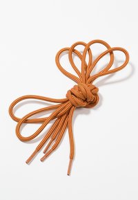 Un cordón de zapato a rayas naranjas y amarillas atado en un nudo decorativo simétrico con cuatro extremos sueltos sobre un fondo blanco.