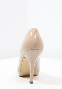 Beige lackläder högklackad sko med spetsig tå och smal klack. Slät textur med minimal sömnadsdetalj baktill.