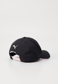 Czarna czapka sportowa wykonana z lekkiego materiału, z zaokrąglonym daszkiem, regulowanym paskiem z tyłu oraz białym logo na plecach.
