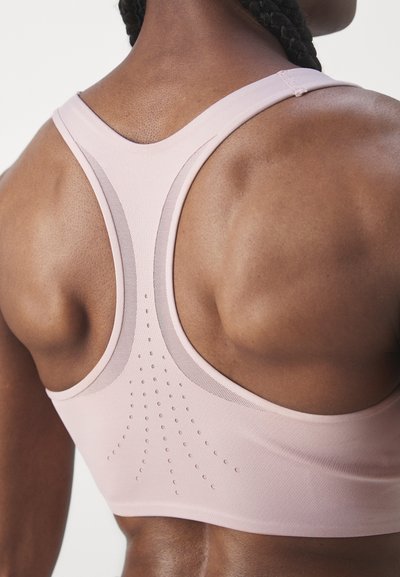 Deportivo rosa claro con diseño de espalda nadadora y detalle texturizado con pequeños puntos elevados para ventilación. Tejido suave y elástico.