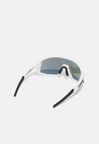 Ochelari de soare sport cu un cadru alb, accente de cauciuc închise la culoare și o lentilă mare gri cu un gradient subtil. Design ușor, care se înfășoară în jurul feței.