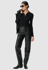 Zwarte geribbelde lange mouwen top met een ritskraag, gecombineerd met hoge zwarte leather broeken en zwarte spitse enkellaarsjes.