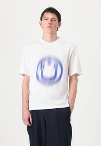 White cotton t-shirt featuring a blue circular graphic design at the center, relaxed fit, short sleeves, and crew neckline.